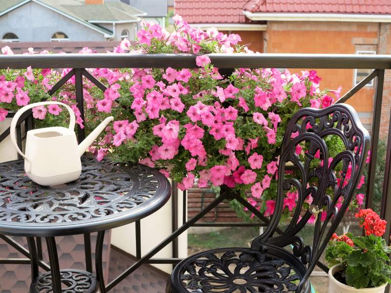 Decoración de balcón con mesa metálica y flores