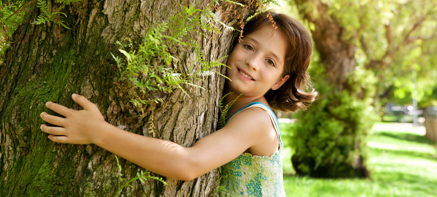 Niña abrazando un árbol - Como cuidar el medio ambiente para las generaciones futuras - Construcciones ecológicas - Sistema EDGE