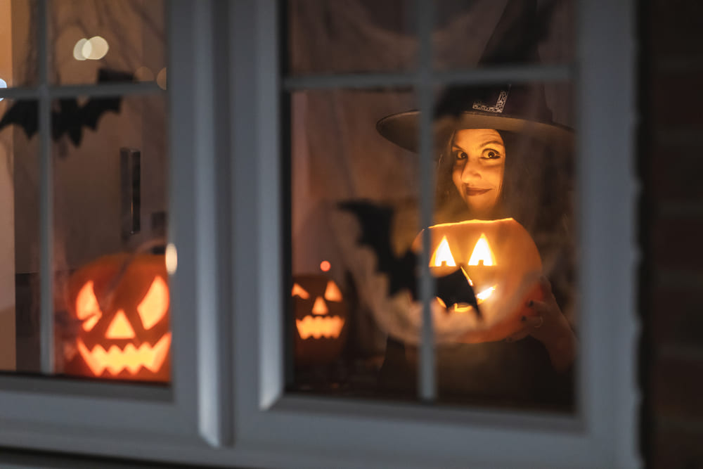 Vista de una niña disfrazada de bruja sosteniendo unos faroles de calabazas de halloween