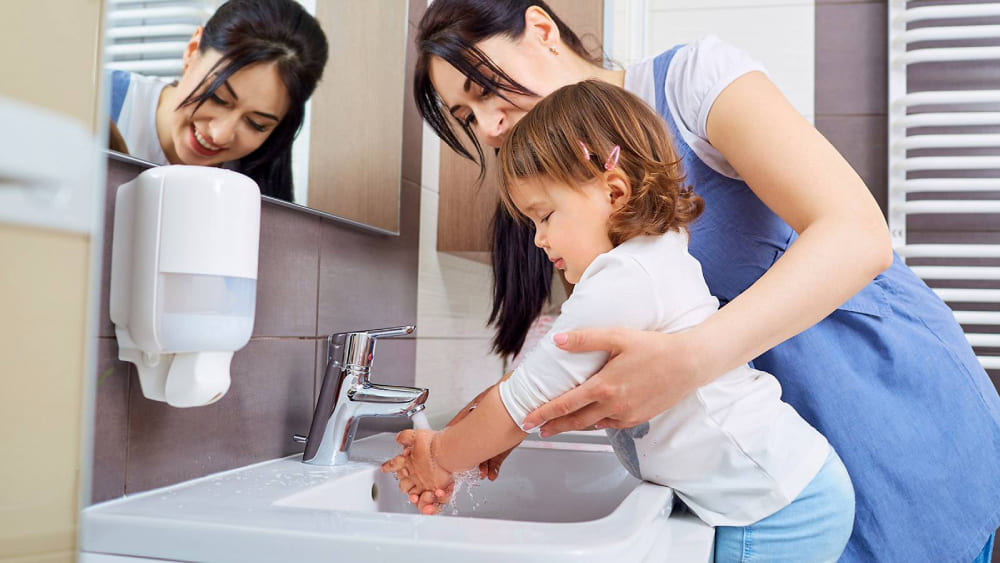 Mamá lavando las manos de su hija 